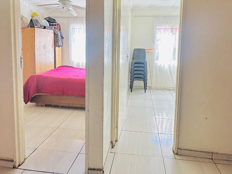 A view from a hallway looking into two adjacent bedrooms, featuring tiled flooring throughout and standard door frames.