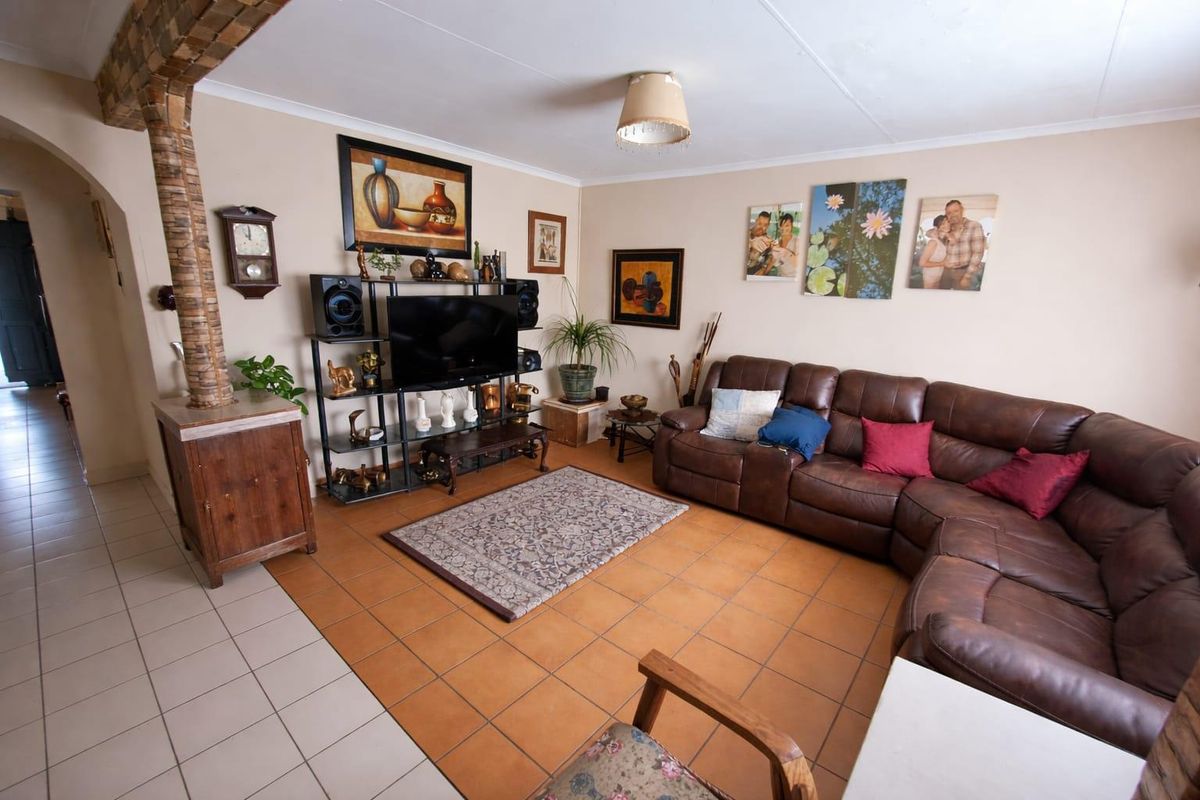 A living room featuring terracotta floor tiles, a brick-clad support column, and neutral wall finishes.