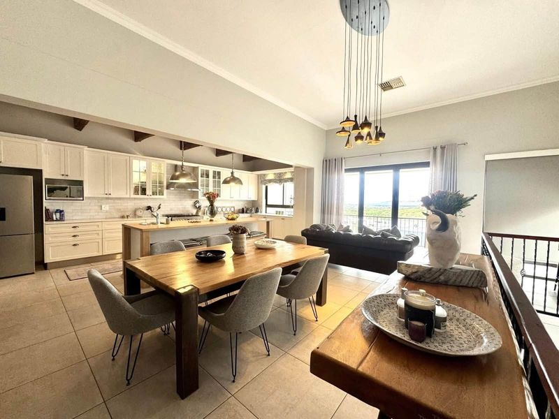 Spacious open-plan living and dining area featuring a modern kitchen with shaker cabinetry, a central island, and seamless access to a balcony with views.