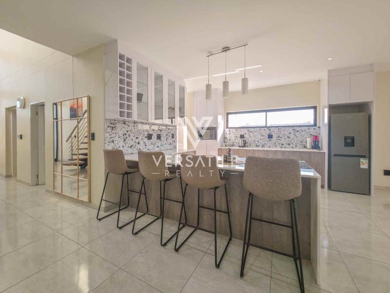 Modern kitchen featuring a central island, sleek built-in cabinetry, terrazzo-style backsplash, and high-quality tiled flooring in an open-plan layout.