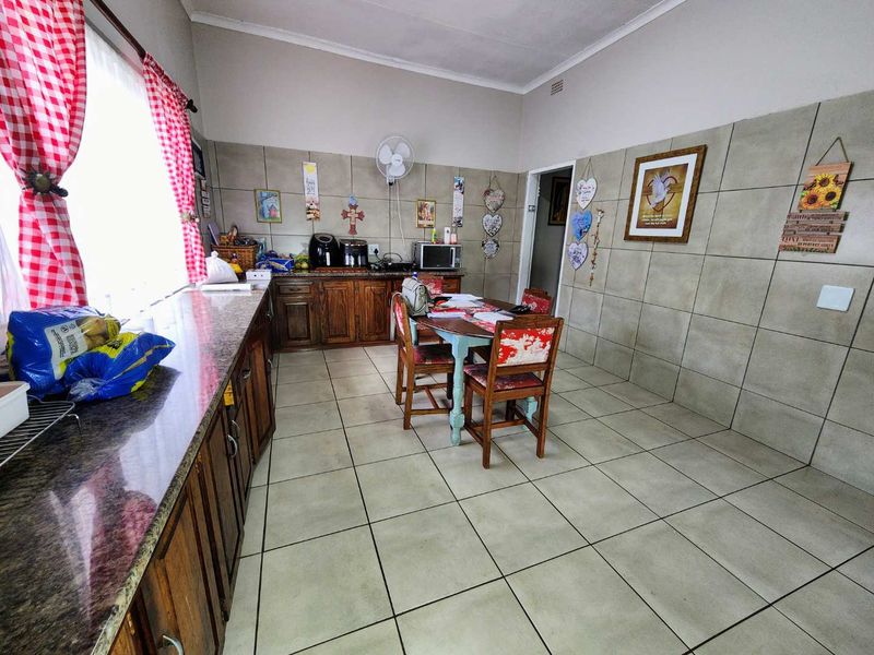 A functional kitchen featuring extensive wall tiling, granite countertops, and traditional wooden cabinetry with ample floor space.