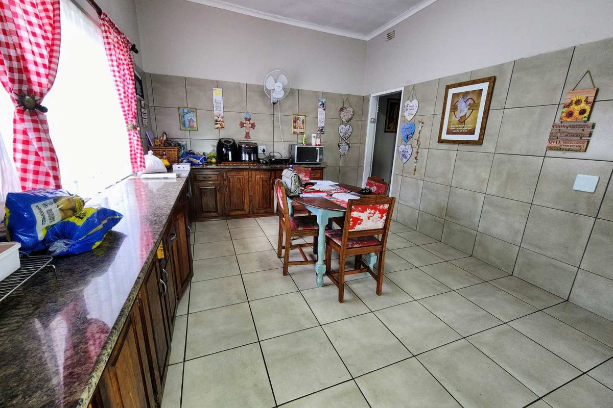 A functional kitchen featuring extensive wall tiling, granite countertops, and traditional wooden cabinetry with ample floor space.