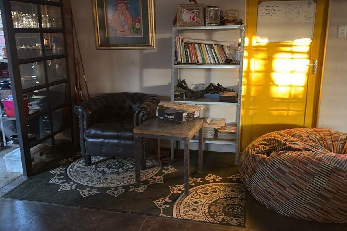 A casual living area featuring a bright yellow door, concrete flooring, and a metal-framed glass partition.