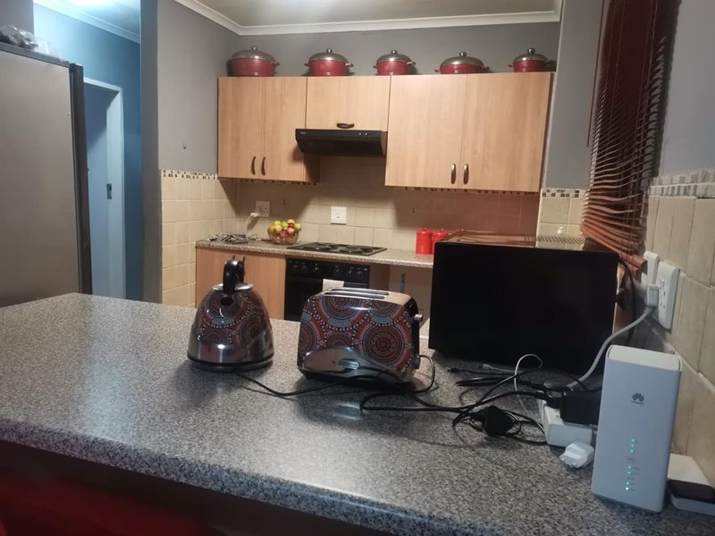 Functional kitchen featuring laminate cabinetry, granite-look countertops, built-in oven, electric hob, and extractor fan with a tiled backsplash.