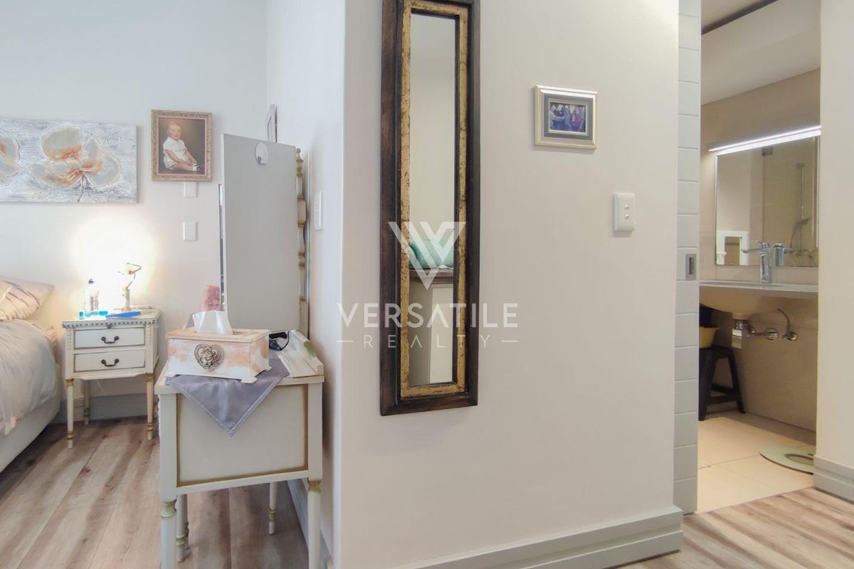 A well-maintained bedroom featuring light-toned laminate flooring and a seamless transition into an adjacent bathroom area.