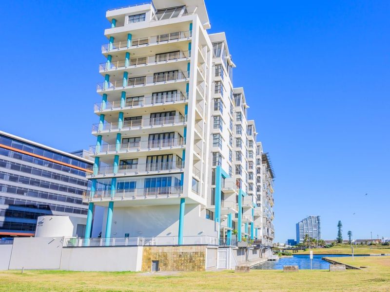 Exterior view of a modern multi-story apartment building featuring stacked balconies with glass balustrades and prominent structural columns.
