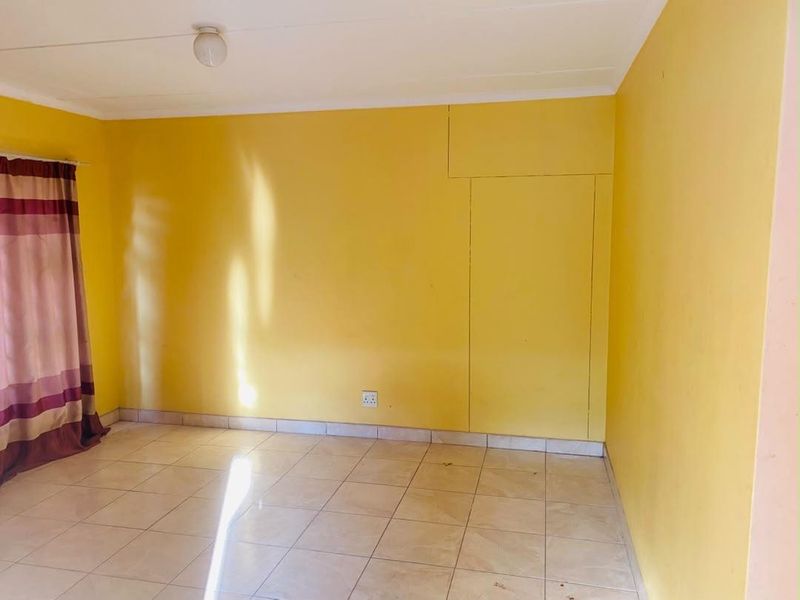 An empty bedroom featuring tiled flooring and a built-in cupboard, ready for personalization.