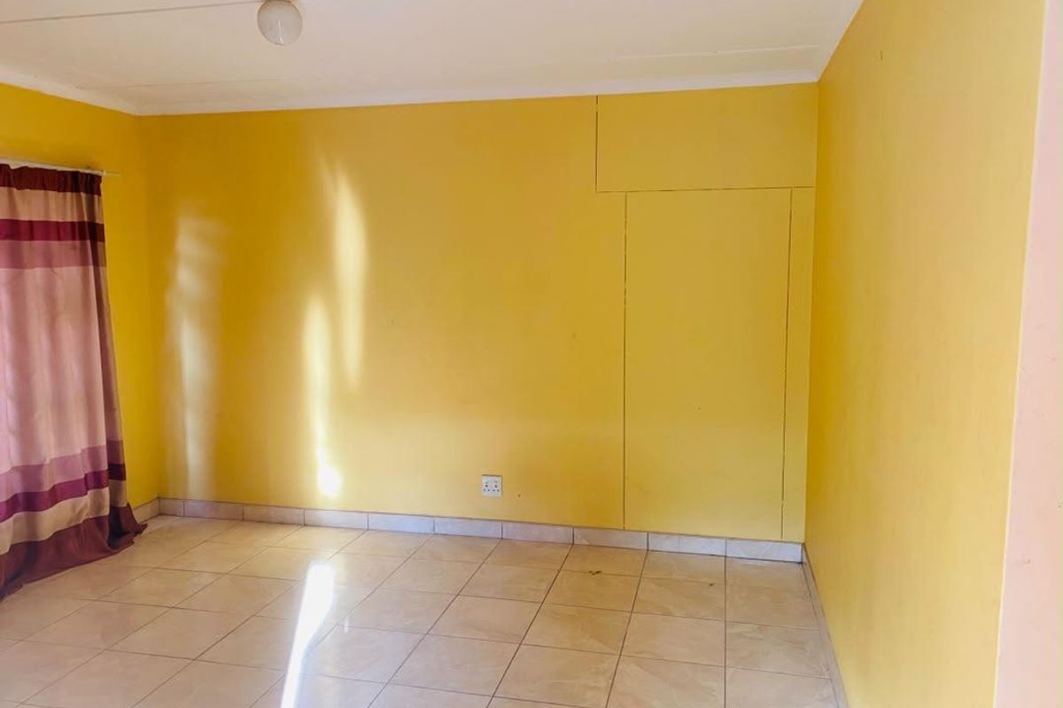 An empty bedroom featuring tiled flooring and a built-in cupboard, ready for personalization.