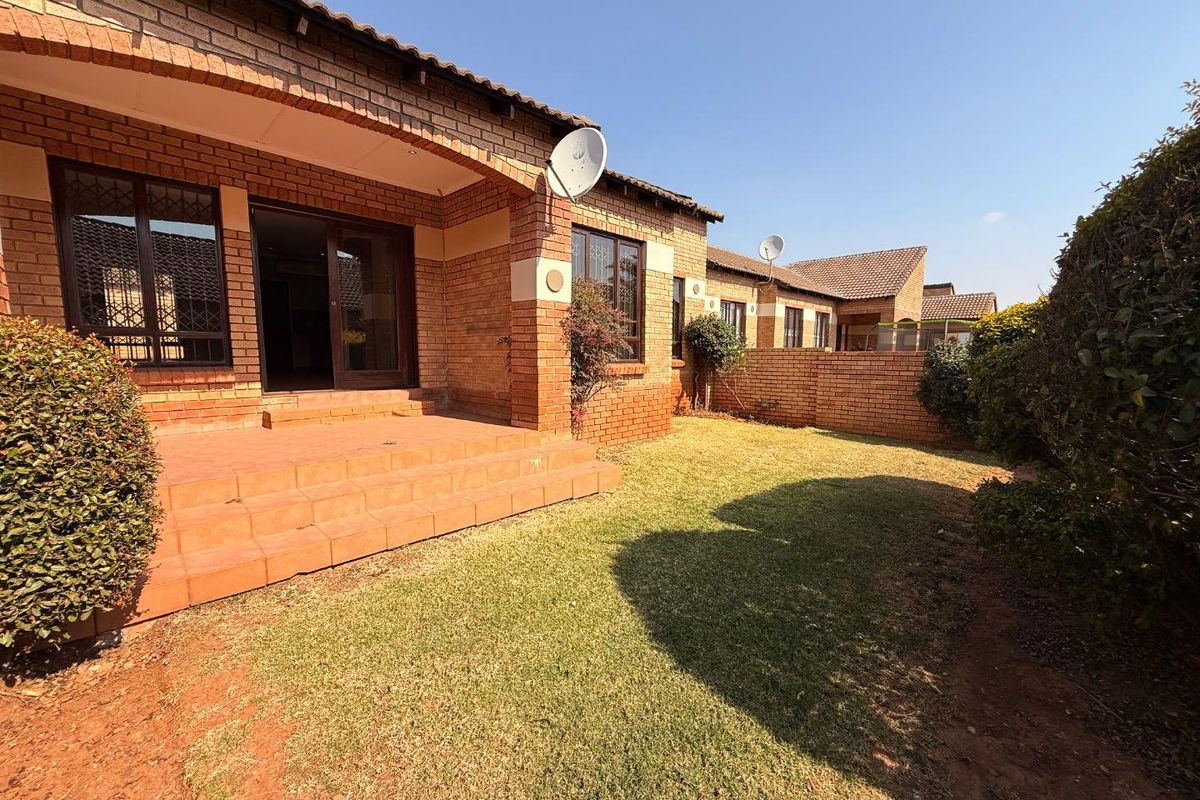 Rear view of the townhouse featuring a covered brick patio, private garden area, and secure sliding door access.