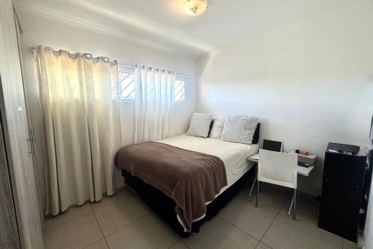 A functional bedroom featuring tiled flooring, built-in wardrobe storage, and horizontal windows with curtain tracks.