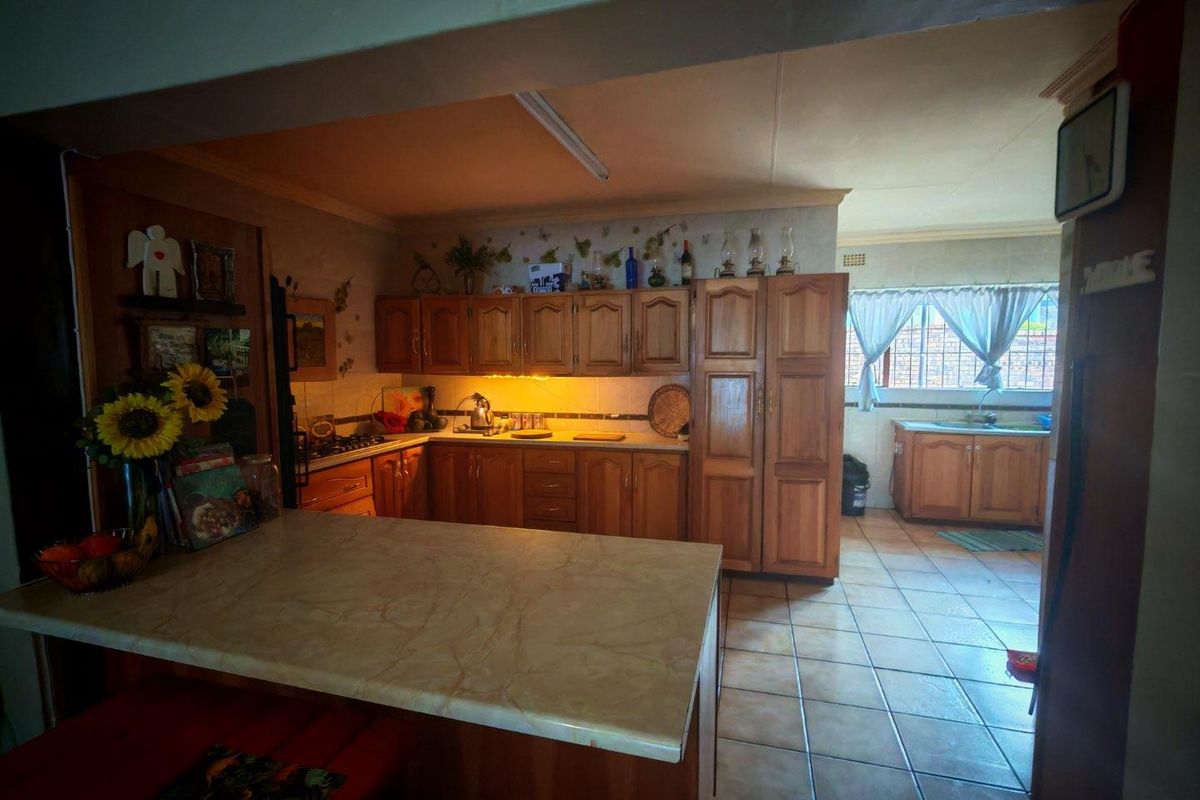 A traditional kitchen featuring wooden cabinetry, tiled flooring, and a breakfast bar, offering a functional layout with ample storage space.