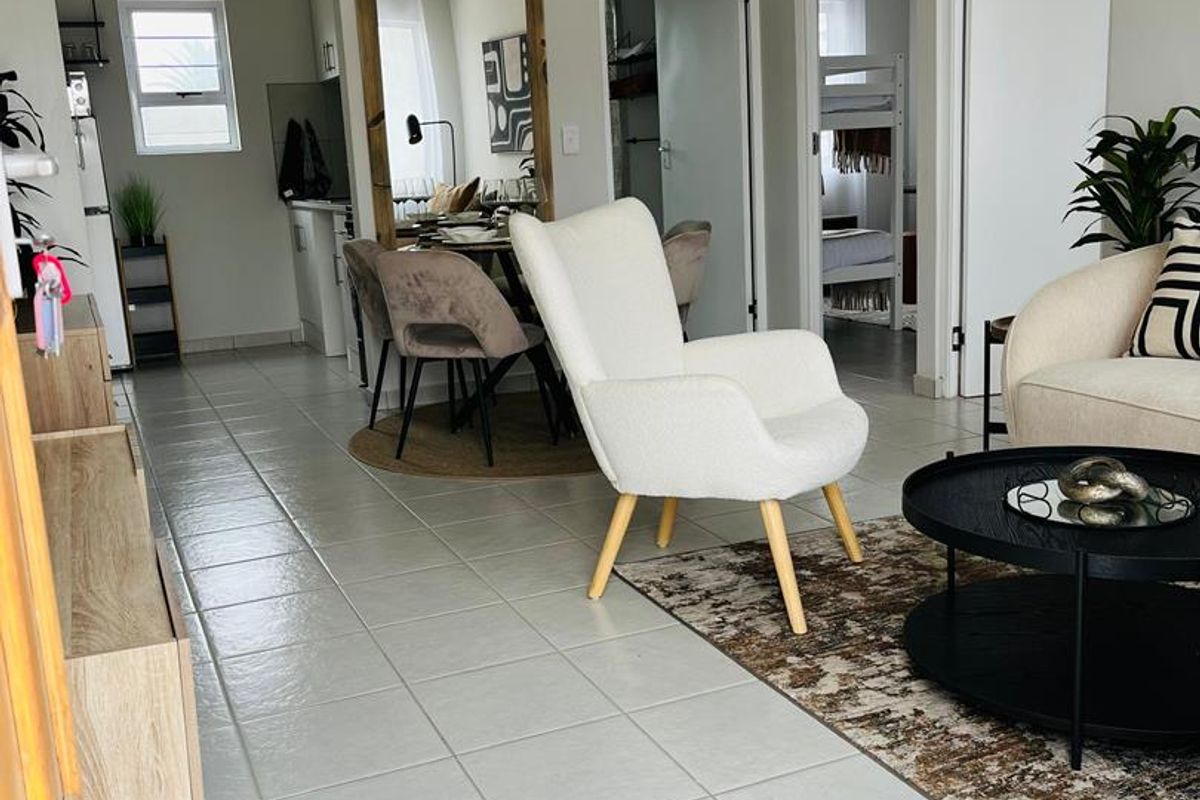 An open-plan living and dining area featuring light-colored tiled flooring, a high tongue and groove ceiling, and direct access to adjacent rooms.