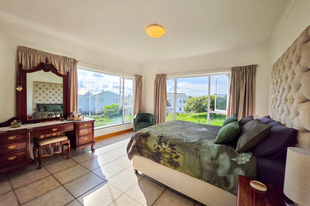 Spacious bedroom featuring large windows that provide ample natural light and views, complemented by tiled flooring and a neutral interior finish.