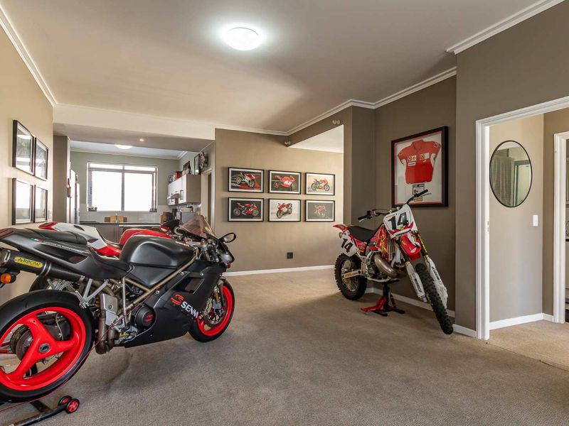 Spacious open-plan living area featuring neutral wall tones, carpeted flooring, and crown molding, with an adjacent kitchen visible in the background.