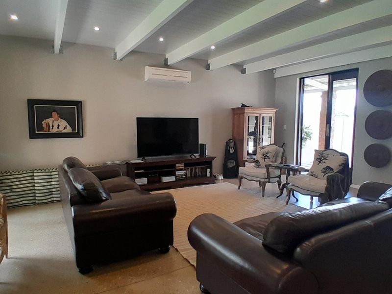 Spacious living room featuring exposed ceiling beams, recessed lighting, a split-system air conditioner, and large sliding glass doors leading to the outdoor area.