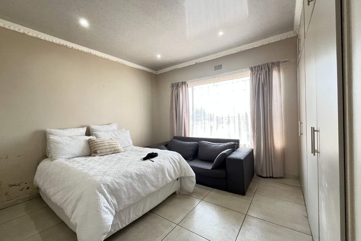 A bedroom featuring tiled flooring, built-in cupboards, and recessed lighting. Note visible wall staining requiring attention.