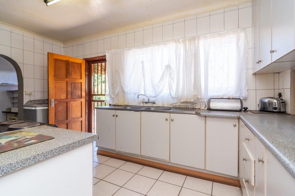 A functional kitchen featuring white cabinetry, laminate countertops, tiled walls, and direct access to an exterior door.