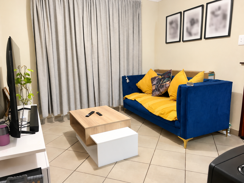 A comfortable living room featuring neutral tiled flooring and full-length curtains, providing a functional and well-lit space for relaxation.