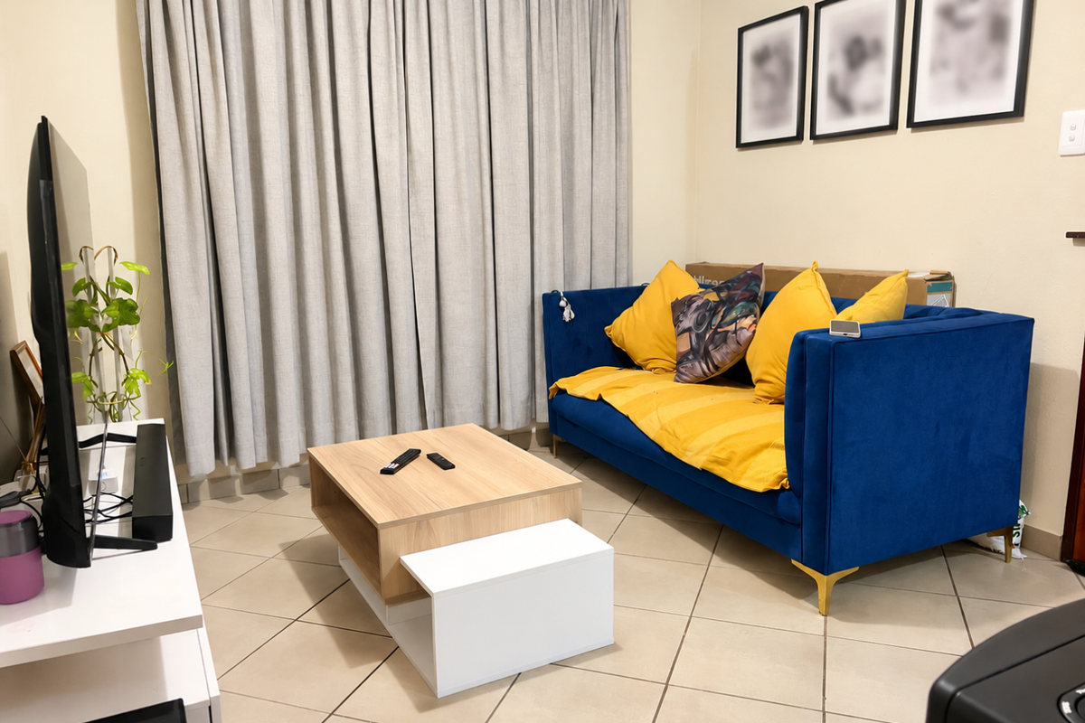 A comfortable living room featuring neutral tiled flooring and full-length curtains, providing a functional and well-lit space for relaxation.