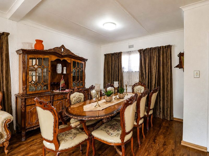 A traditional dining room featuring laminate flooring and classic ceiling cornicing, providing a formal space for family meals and entertaining.
