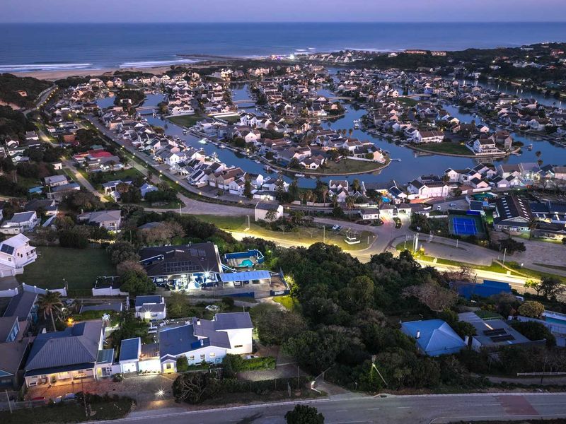 Aerial view of the guest house property at dusk, showcasing the surrounding coastal estate, swimming pool, and solar panel installation.