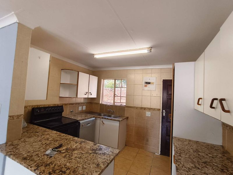 A functional kitchen featuring granite countertops, tiled backsplash, and ample built-in cabinetry, offering a practical layout ready for modernization.