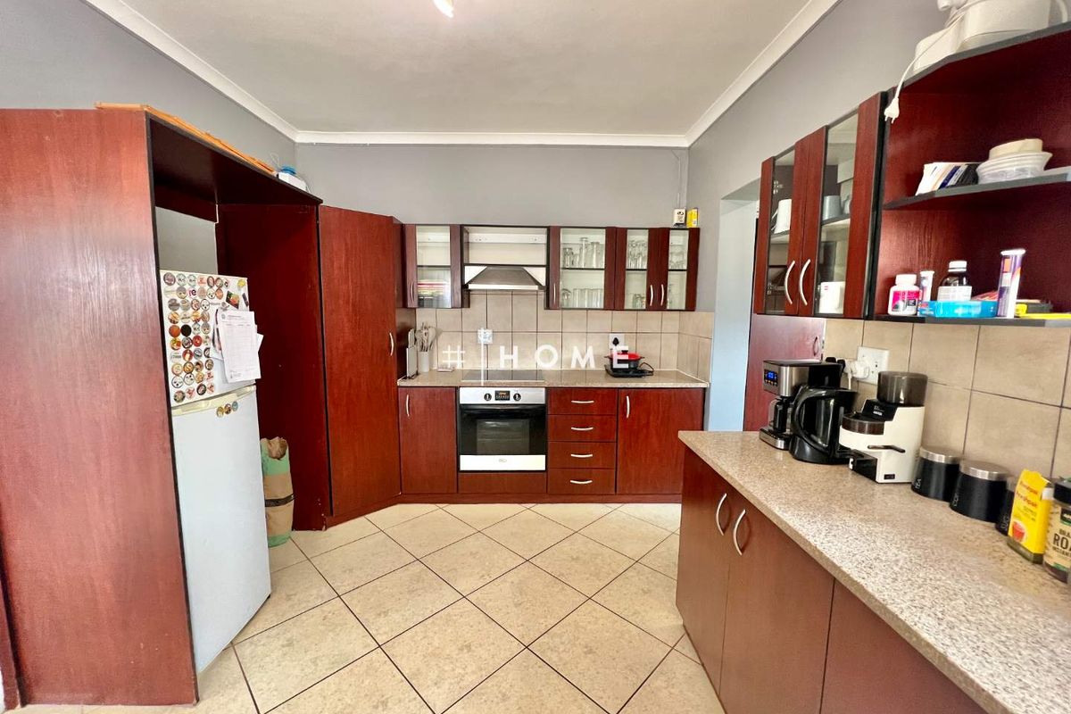 A functional kitchen featuring dark wood cabinetry, tiled countertops, a built-in oven, and a stainless steel extractor fan.