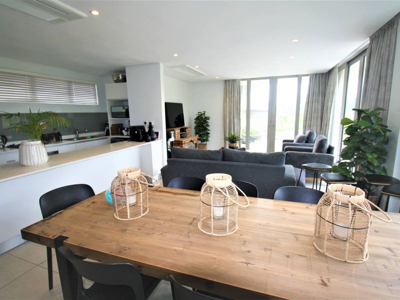 Spacious open-plan living area featuring a modern kitchen with island, tiled floors, and large glass sliding doors leading to an outdoor space.