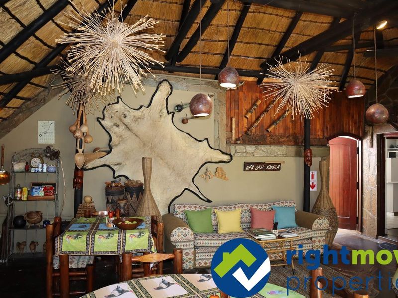 A rustic living area featuring a traditional thatched roof with exposed timber rafters and stone wall accents, creating a warm, authentic atmosphere.