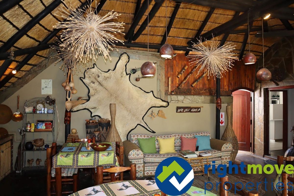 A rustic living area featuring a traditional thatched roof with exposed timber rafters and stone wall accents, creating a warm, authentic atmosphere.