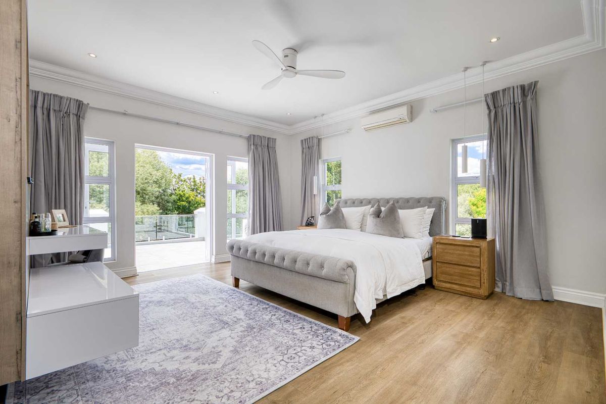 Spacious bedroom featuring light wood flooring, recessed lighting, a ceiling fan, split-system air conditioning, and direct access to a private balcony.