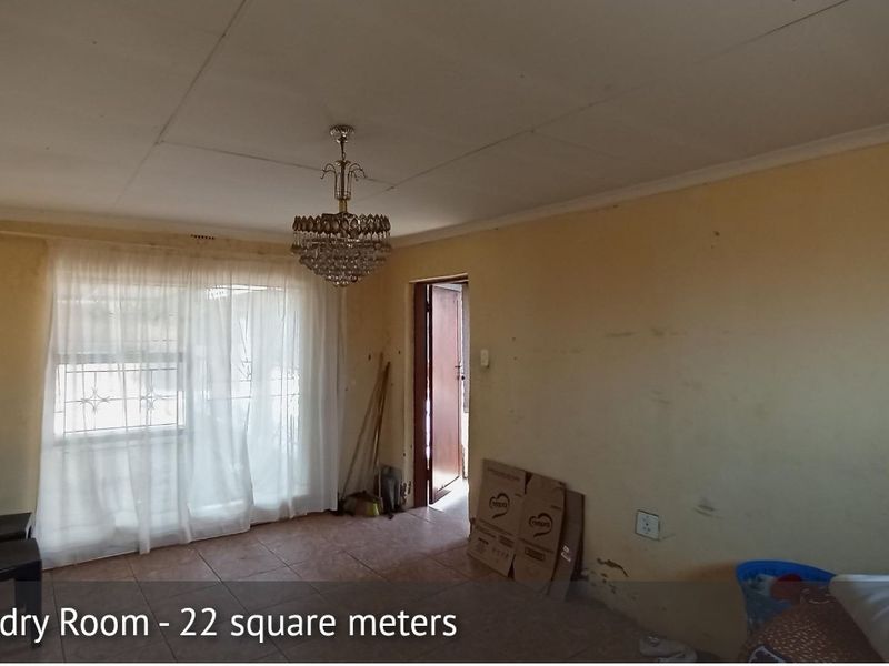 Spacious living area featuring tiled flooring and a decorative chandelier, requiring cosmetic updates to the walls and finishes.