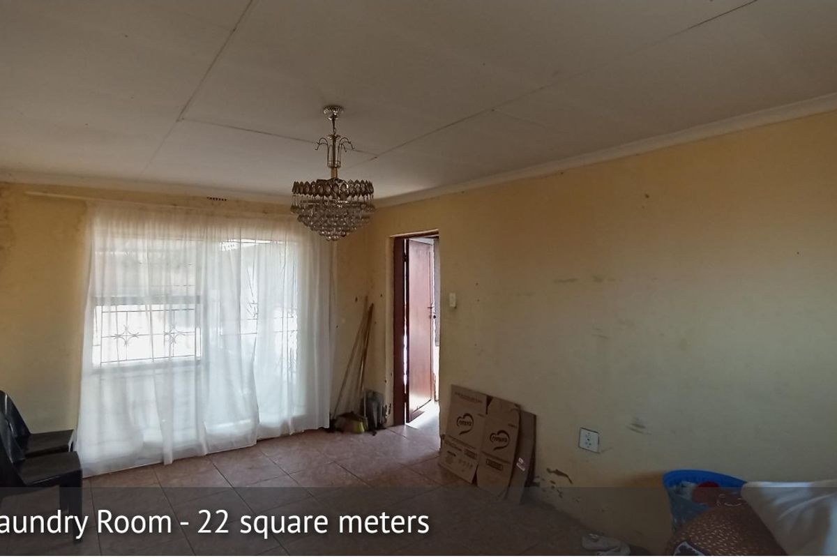 Spacious living area featuring tiled flooring and a decorative chandelier, requiring cosmetic updates to the walls and finishes.