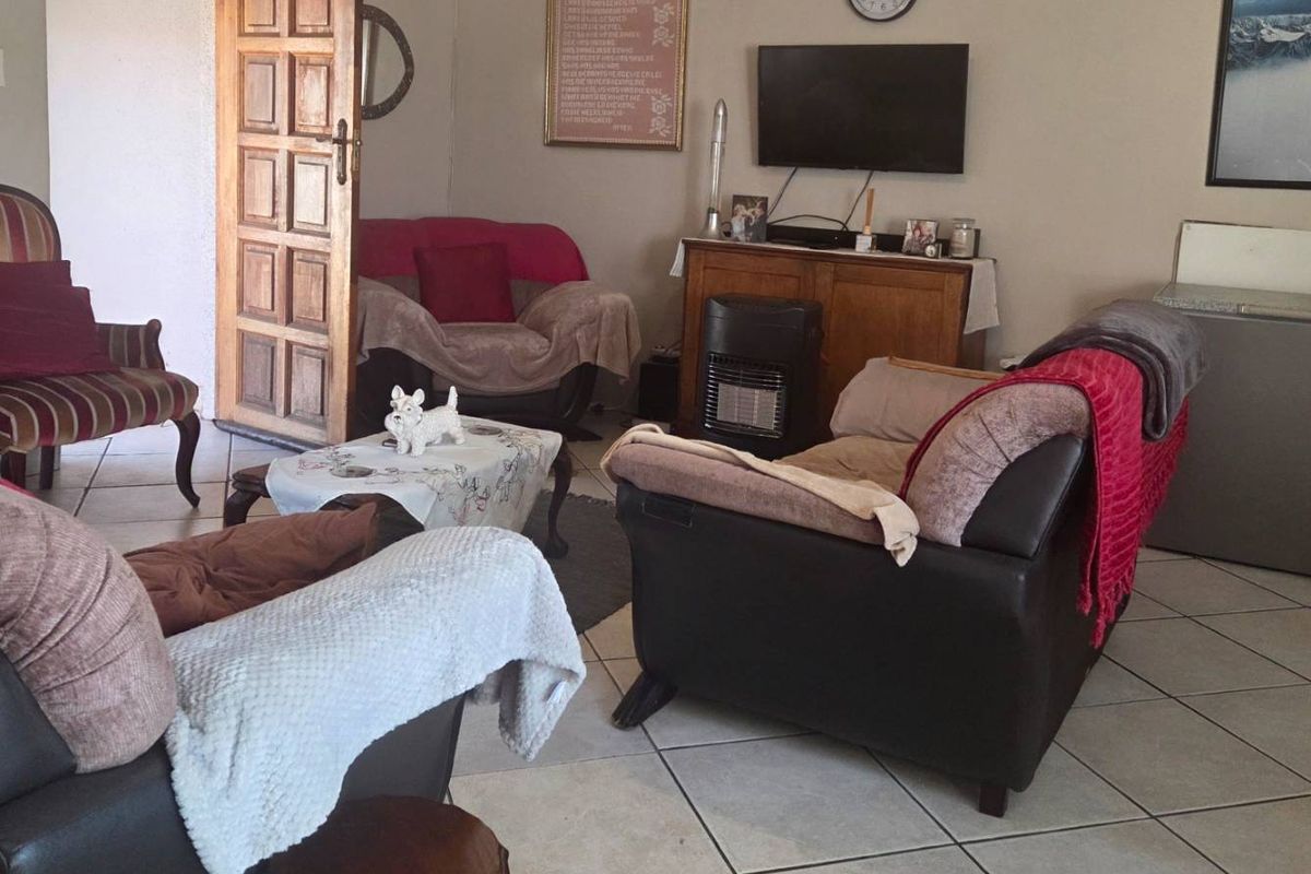 A living room area featuring tiled flooring and a solid wood panel door, providing a functional and lived-in space.