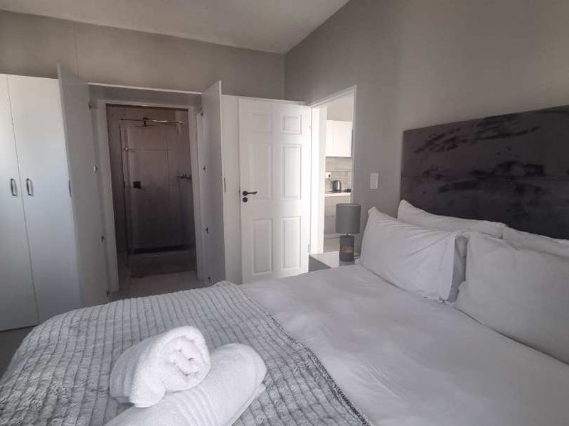 A well-maintained bedroom featuring built-in cupboards and direct access to an en-suite bathroom with neutral finishes.