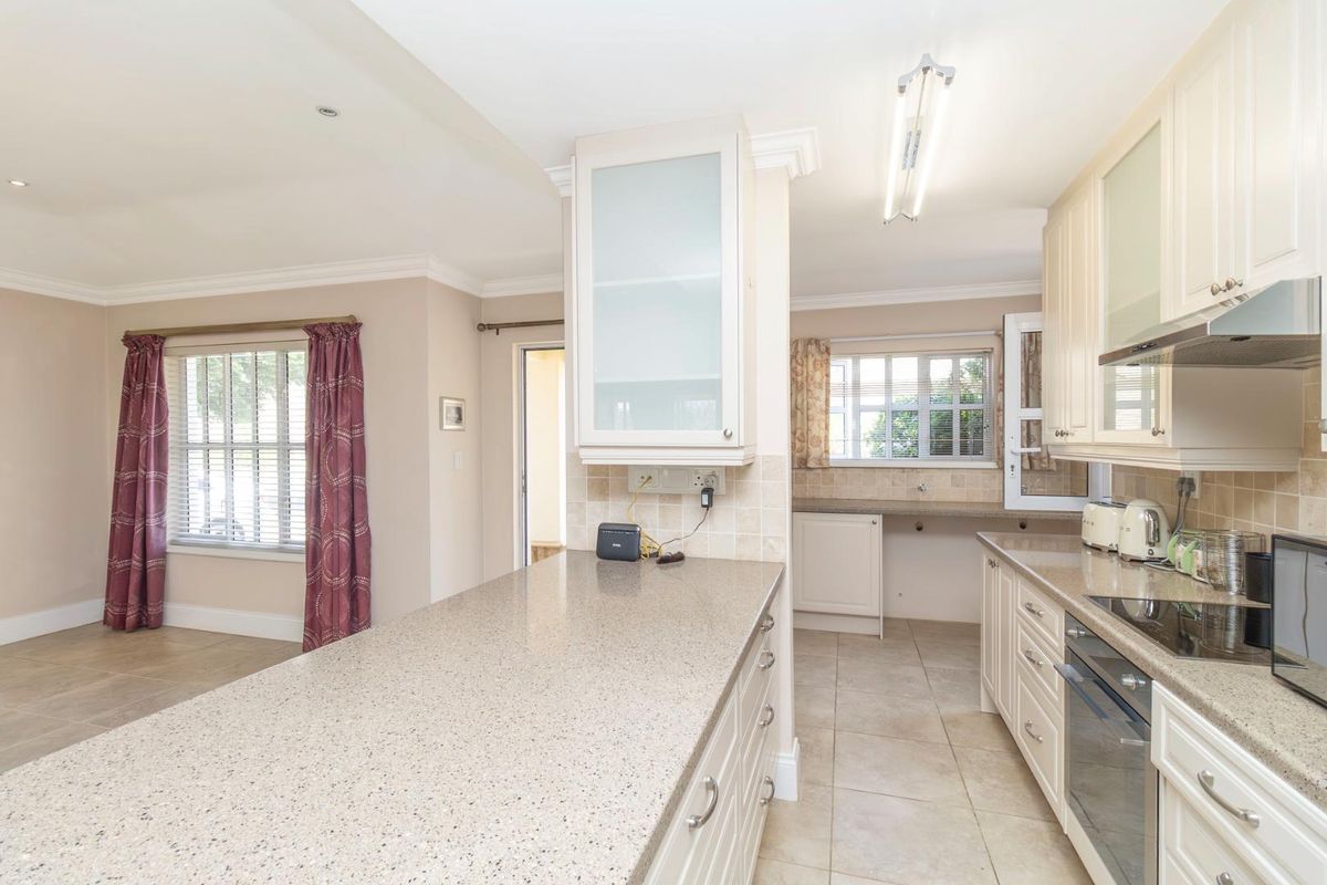 A functional kitchen featuring stone-look countertops, built-in cabinetry, an integrated oven, and a hob, with an open-plan layout connecting to the adjacent living area.