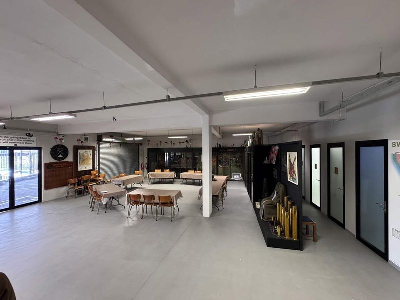 Spacious open-plan clubhouse or utility hall featuring industrial-style exposed lighting, concrete flooring, and multiple access points, suitable for versatile commercial or community use.