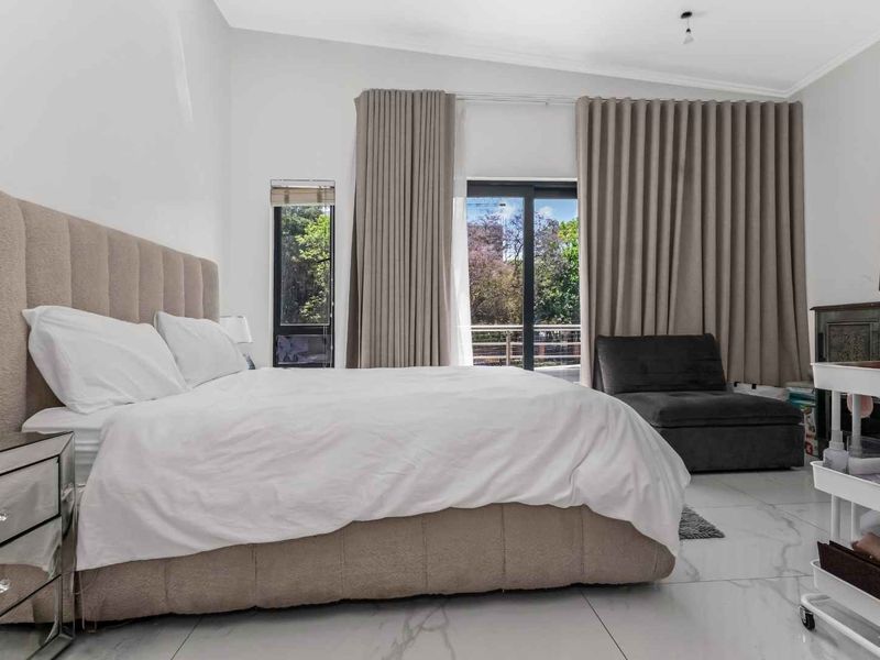 Spacious bedroom featuring large format tiled flooring, neutral wall finishes, and a sliding glass door providing access to an outdoor balcony area.
