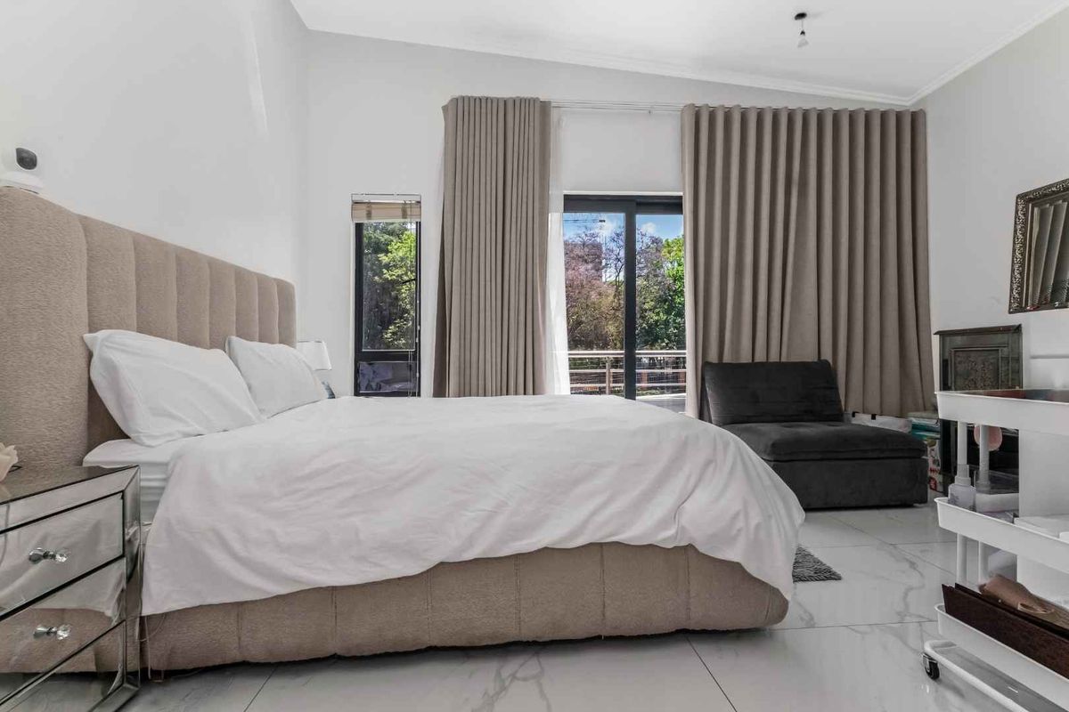 Spacious bedroom featuring large format tiled flooring, neutral wall finishes, and a sliding glass door providing access to an outdoor balcony area.