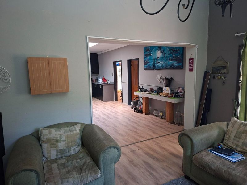 Open plan living area featuring laminate flooring with a view through to the kitchen and adjacent rooms.