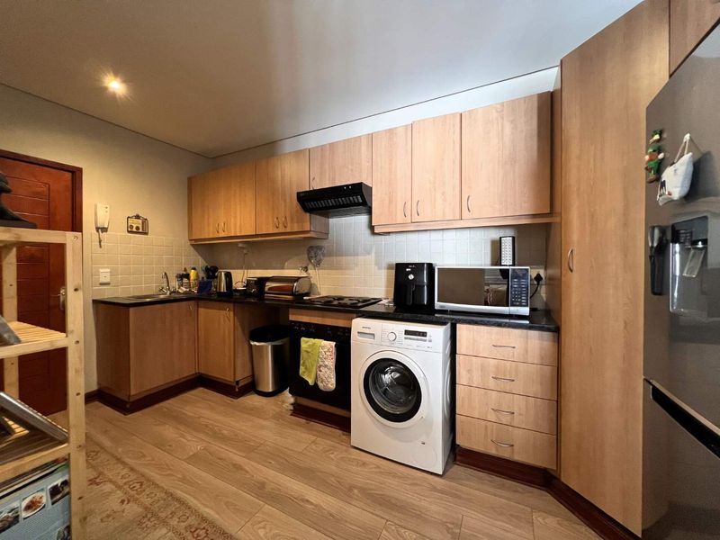Functional kitchen featuring laminate cabinetry, granite countertops, built-in oven, hob, extractor fan, and tiled backsplash with integrated laundry plumbing.