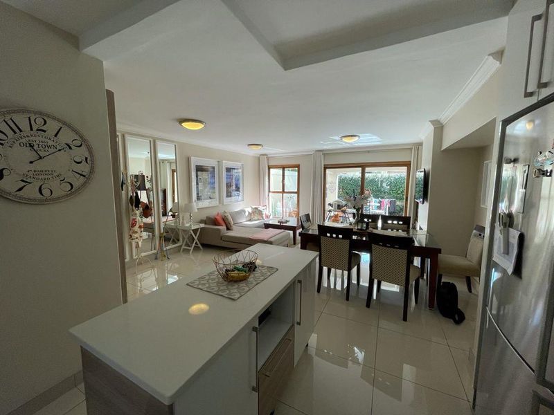 Spacious open-plan living and dining area featuring tiled floors, a modern kitchen island, and sliding doors leading to an outdoor patio space.