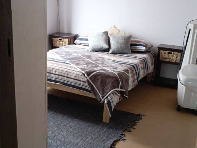 A bedroom featuring exposed timber ceiling beams and a simple, functional layout with basic floor finishes.