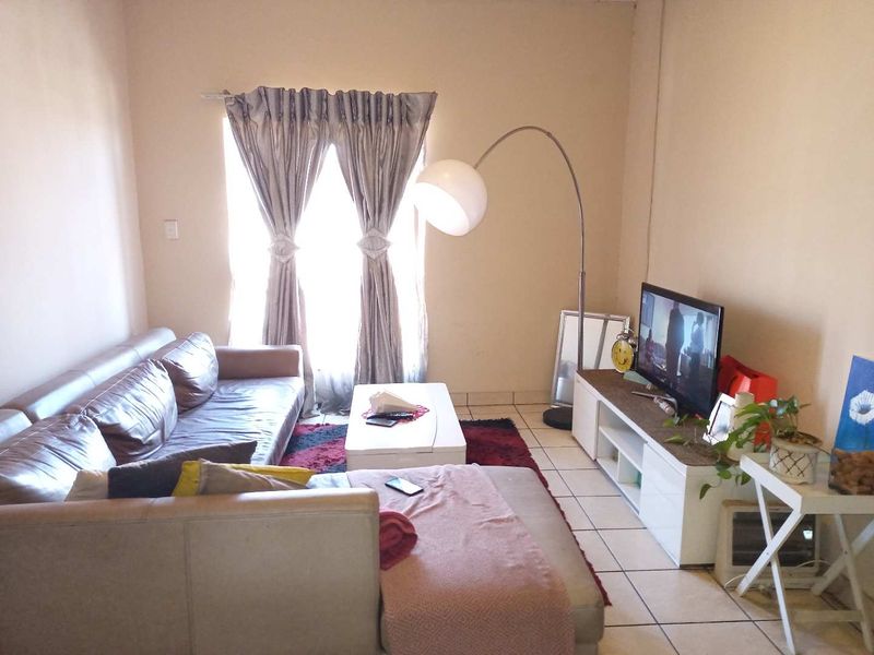 A living room featuring tiled flooring and a window with curtains, providing a functional and comfortable space for relaxation.