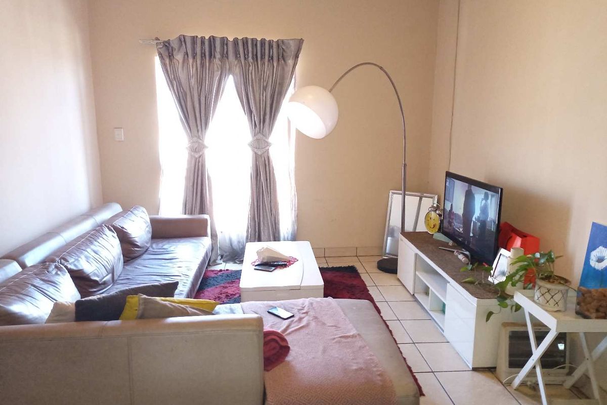 A living room featuring tiled flooring and a window with curtains, providing a functional and comfortable space for relaxation.
