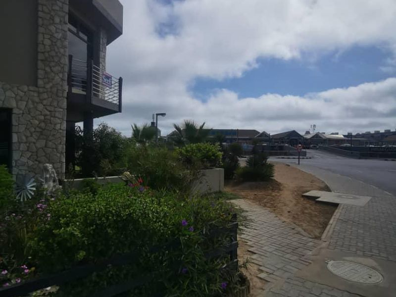 Street-level view of the property exterior featuring stone cladding, a paved walkway, and a balcony overlooking the road.