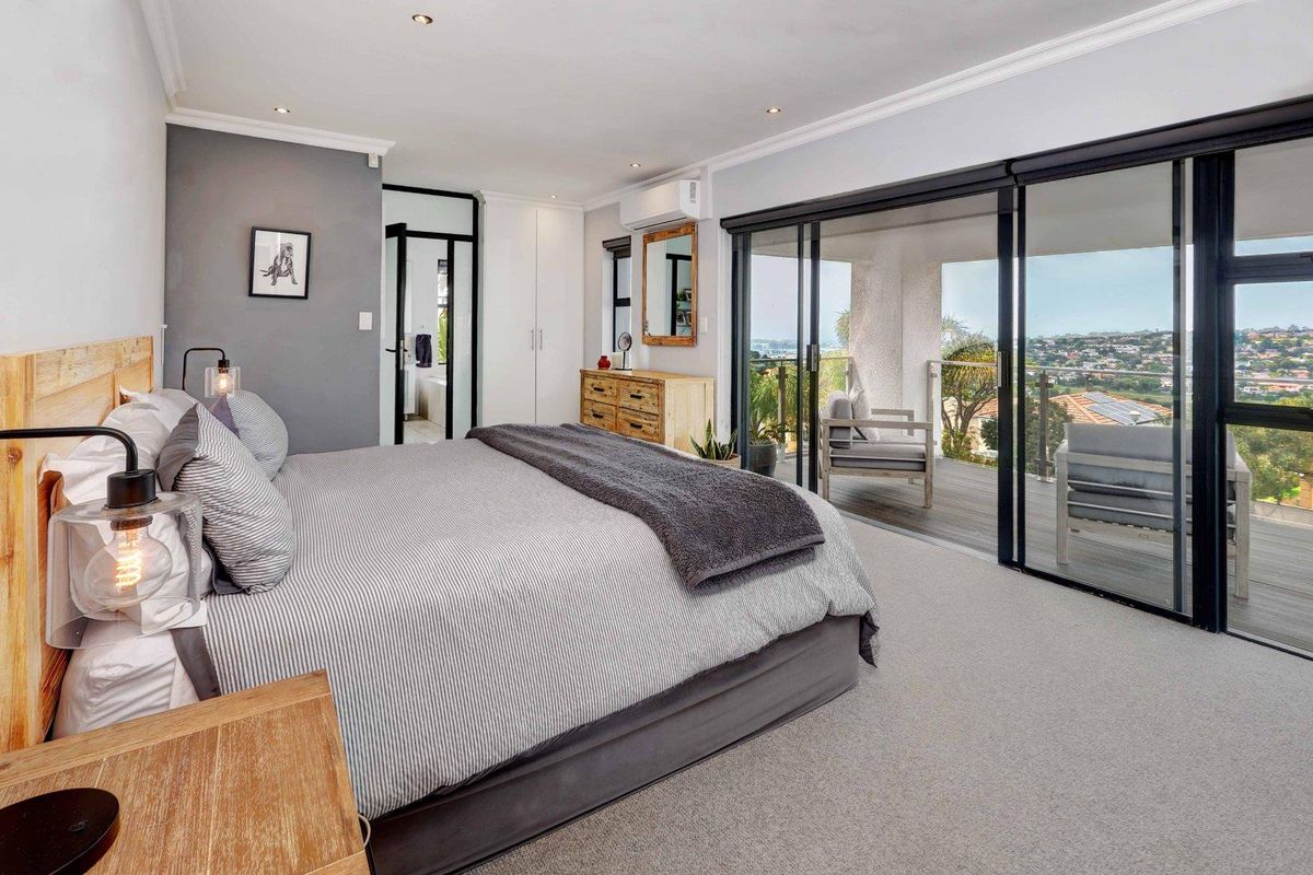 Spacious bedroom featuring built-in cupboards, recessed lighting, and large sliding glass doors opening onto a private balcony with scenic views.