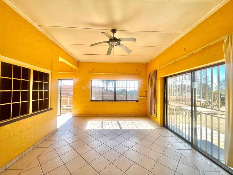 An empty living area featuring tiled floors, a ceiling fan, and large sliding glass doors providing access to the exterior.
