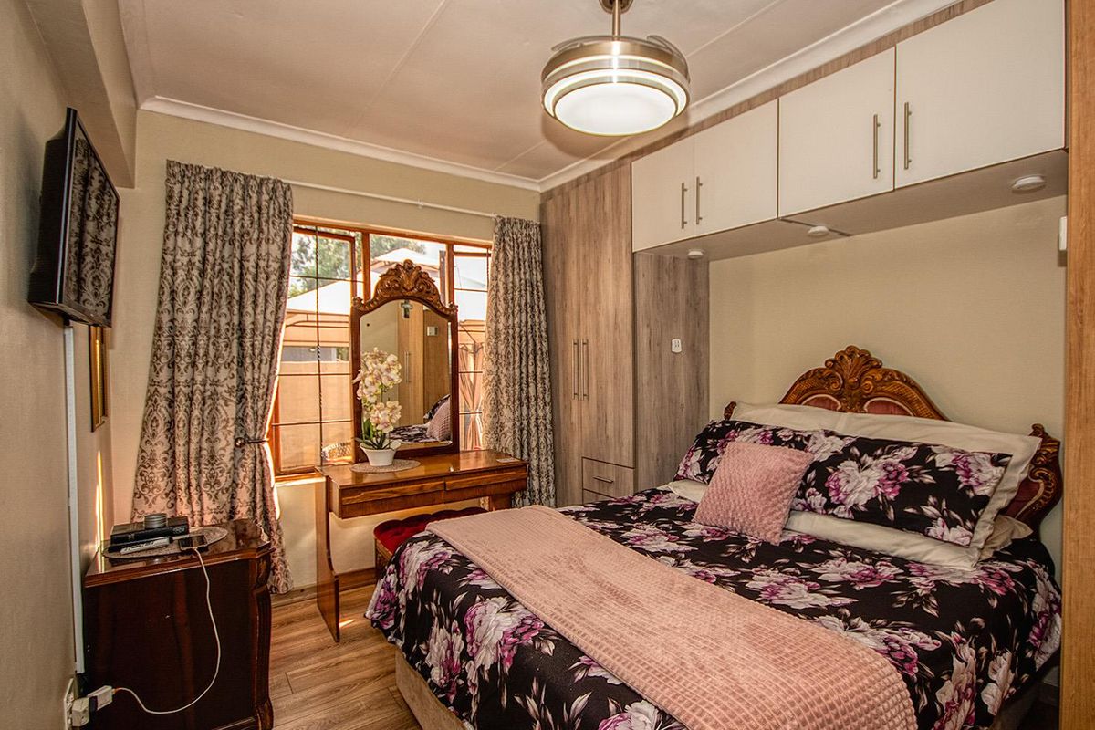 A well-maintained bedroom featuring built-in cabinetry, overhead storage units, and wood-look flooring, providing efficient storage and a comfortable living space.