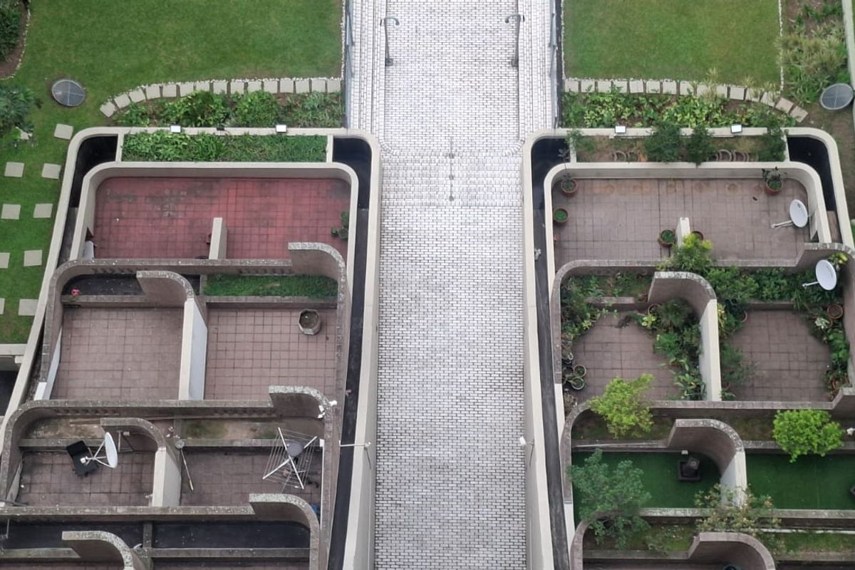 An elevated aerial view of the apartment complex grounds, featuring paved walkways, landscaped garden areas, and private patio spaces.
